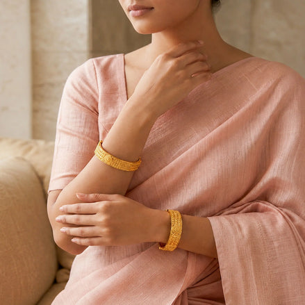 gold plated round emblem textured bangles on woman hand DCC1018